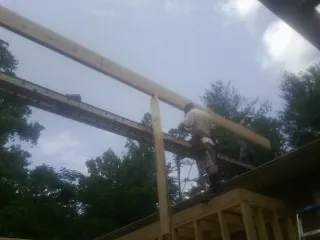 Carpenter setting a ridge beam over a new addition frame — Ice Dam Removal by Roofing Brothers in Spring Valley