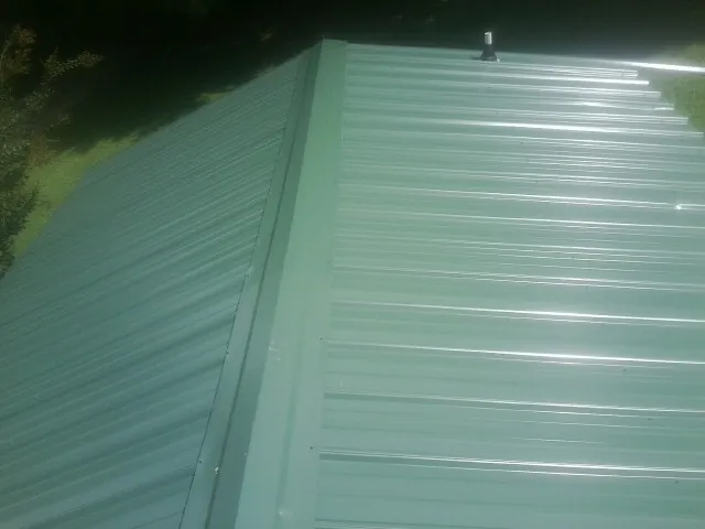 New green metal panels meeting at the ridge of a roof — Flat Roof Repair work by our crew in Spring Valley