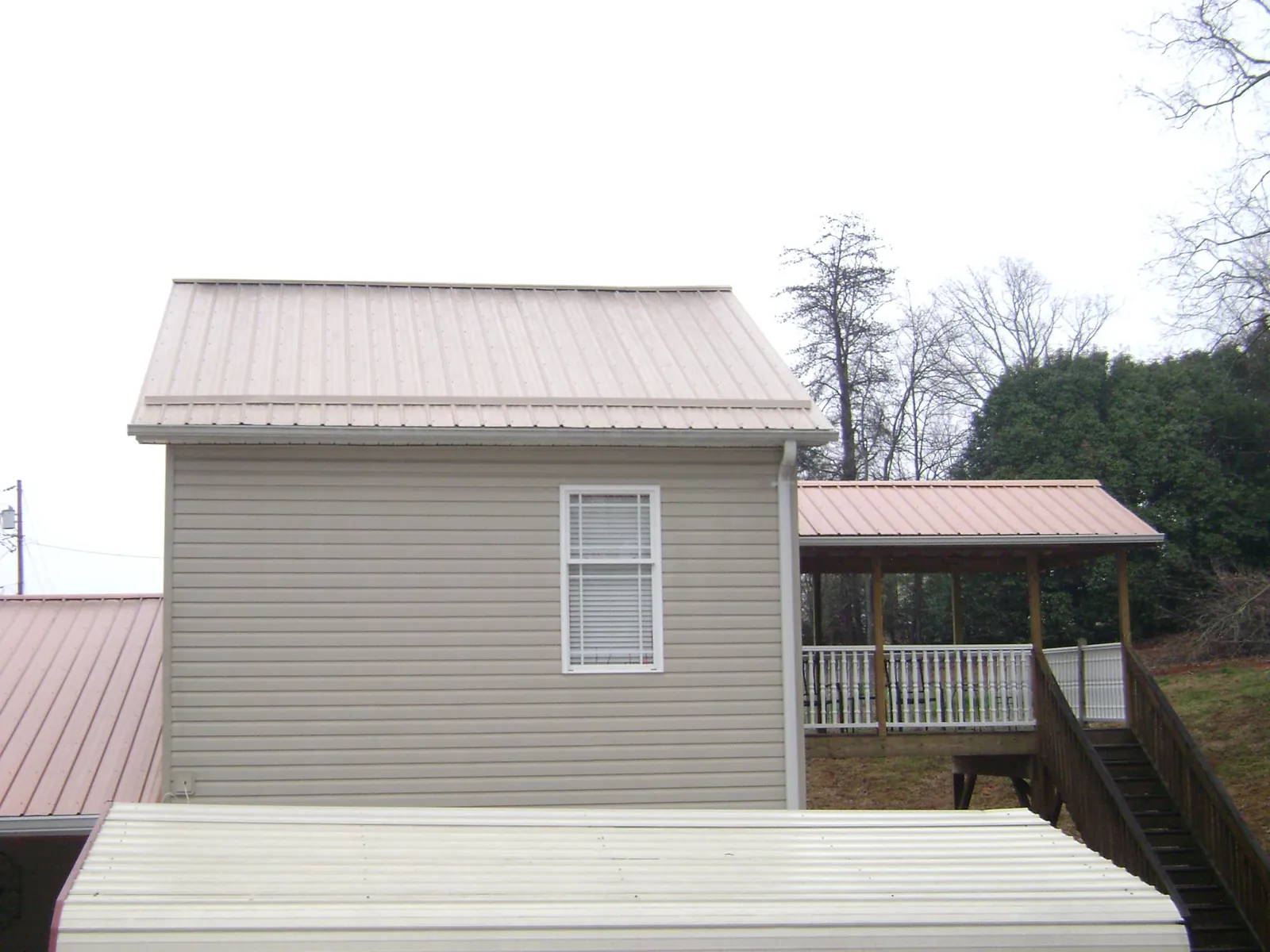 Tan metal roofs on a two story addition and attached porch, from a Roof Replacement job in Spring Valley